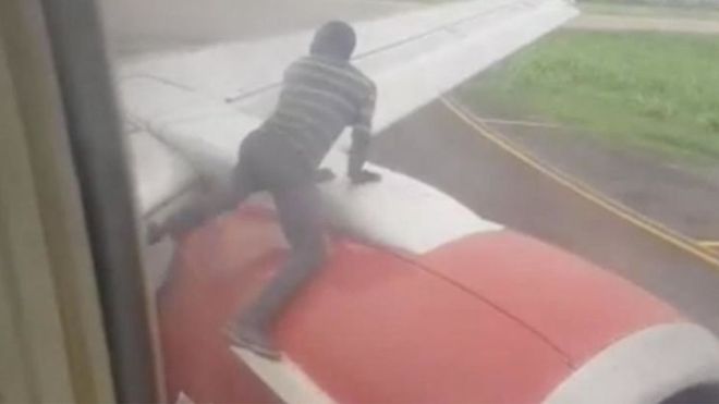 Un homme arrêté sur l'aile d'un avion, peu avant le décollage